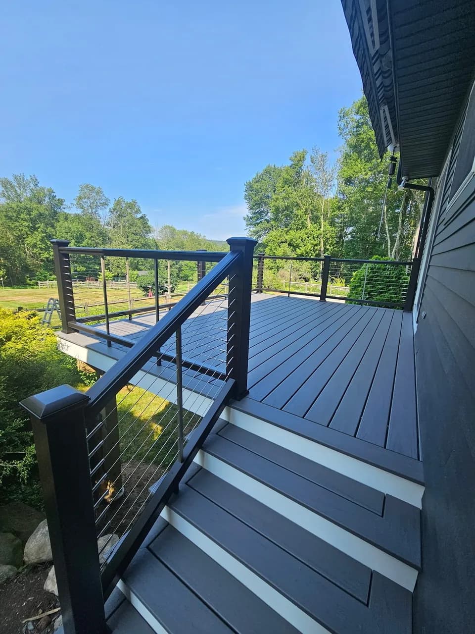 Gray deck and steps with dark cable railing, shared by Mo on Entryways’ Google Maps listing.